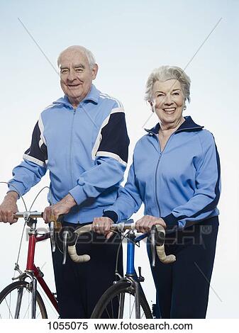 Stock Photography - Senior man and woman smiling holding racing bicycles. Fotosearch