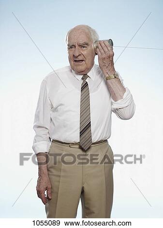 Senior man comically strains to listen on tin can phone View Large Photo Image Stock Photo - Senior man comically strains to listen on tin can phone. Fotosearch