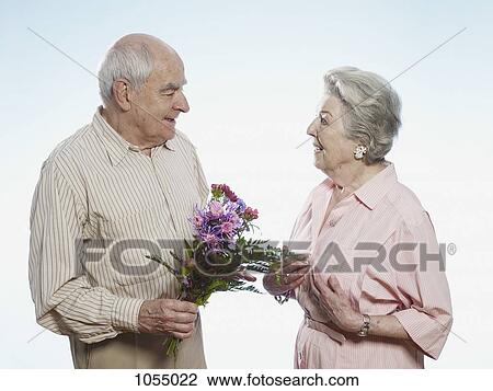 Senior man gives senior woman flowers View Large Photo Image Stock Image - Senior man gives senior woman flowers. Fotosearch