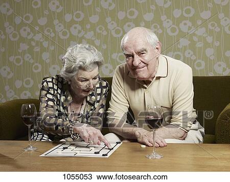 Stock Image - Senior man grimaces as senior woman contemplates a move playing muehle. Fotosearch