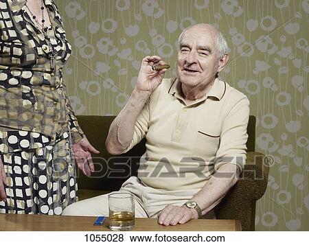 Senior man sitting on couch smoking cigar View Large Photo Image Stock Photo - Senior man sitting on couch smoking cigar. Fotosearch