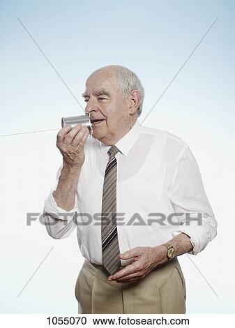 Senior man speaks into tin can phone View Large Photo Image Stock Image - Senior man speaks into tin can phone. Fotosearch