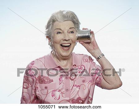 Senior woman comically listens to tin can phone View Large Photo Image Stock Image - Senior woman comically listens to tin can phone. Fotosearch