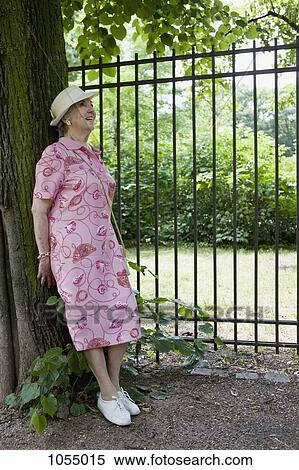 Senior woman happily leaning against tree in park View Large Photo Image Stock Photography - Senior woman happily leaning against tree in park. Fotosearch