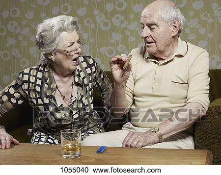 Senior woman looks shocked as senior man smokes cigar View Large Photo Image Stock Image - Senior woman looks shocked as senior man smokes cigar . Fotosearch