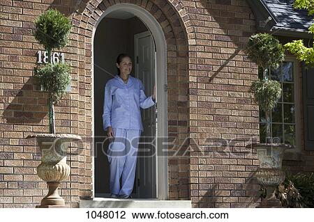 Smiling woman wearing Pajamas leans on front door and looks out View Large Photo Image Stock Image - Smiling woman wearing Pajamas leans on front door and looks out. Fotosearch