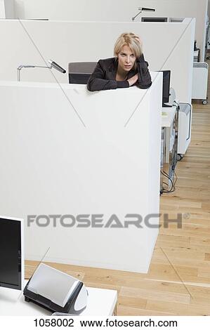 Stock Image - Stressed woman leaning on office cubicle. Fotosearch