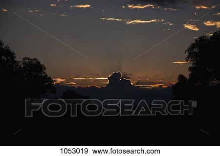 Sun setting behind clouds in a remote location View Large Photo Image Stock Photo - Sun setting behind clouds in a remote location. Fotosearch