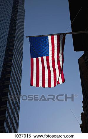 The American flag shown between two tall buildings with a backdrop of a clear blue sky View Large Photo Image Stock Photography - The American flag shown between two tall buildings with a backdrop of a clear blue sky. Fotosearch