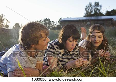 Three friends lying down amongst the timothy grass View Large Photo Image Stock Photograph - Three friends lying down amongst the timothy grass . Fotosearch