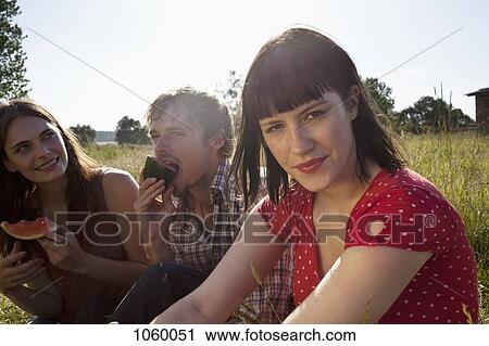 Three people side by side in a field eating melon View Large Photo Image Stock Image - Three people side by side in a field eating melon. Fotosearch
