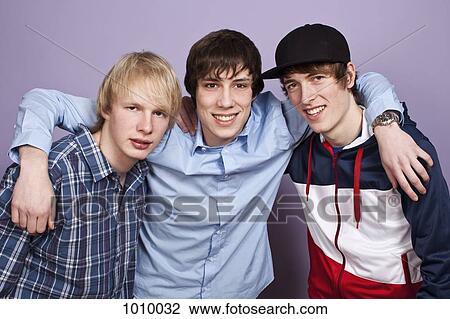 Stock Image - Three teenage boys, portrait, studio shot. Fotosearch
