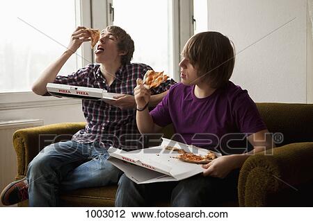 Stock Image - Two boys eating delivery pizza . Fotosearch