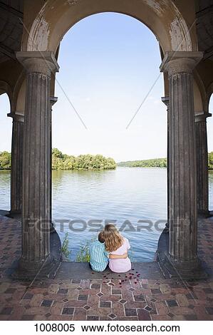 Two children sitting together under an arch next to a lake View Large Photo Image Stock Photography - Two children sitting together under an arch next to a lake. Fotosearch