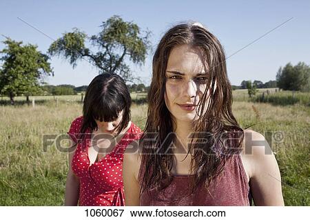 Two cool girls standing in field with one looking at camera View Large Photo Image Stock Photo - Two cool girls standing in field with one looking at camera. Fotosearch