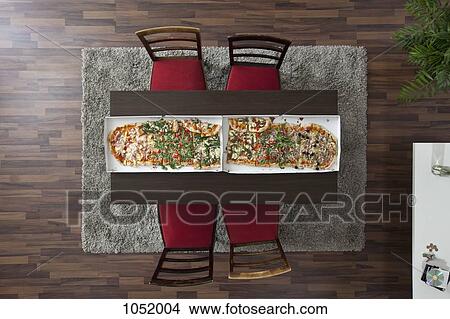 Two large pizzas side by side running the length of a table, overhead view View Large Photo Image Picture - Two large pizzas side by side running the length of a table, overhead view. Fotosearch