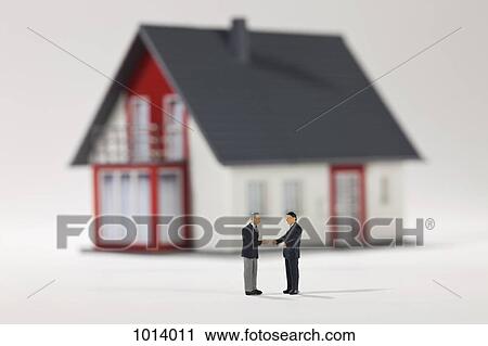Two miniature businessmen figurines shaking hands in front of a house View Large Photo Image Stock Image - Two miniature businessmen figurines shaking hands in front of a house. Fotosearch