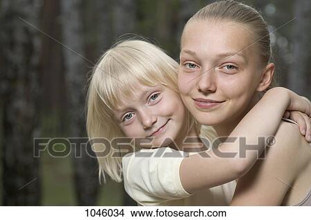 Two sisters embracing, outdoors View Large Photo Image Picture - Two sisters embracing, outdoors. Fotosearch