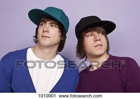 Two teenage boys wearing baseball caps looking away, studio shot View Large Photo Image Stock Image - Two teenage boys wearing baseball caps looking away, studio shot. Fotosearch