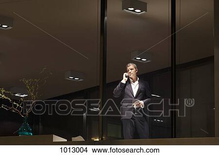 Well dressed man looks through window while on the phone and holding a glass of wine. View Large Photo Image Picture - Well dressed man looks through window while on the phone and holding a glass of wine.. Fotosearch