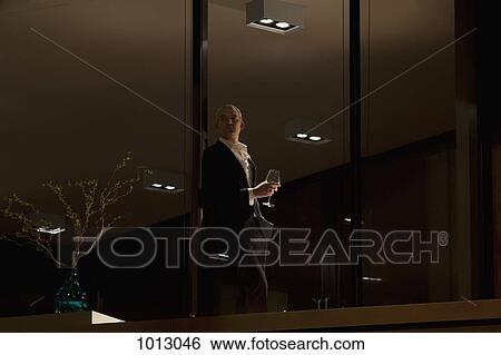 Well dressed man with wine glass looking out window of apartment. View Large Photo Image Stock Photograph - Well dressed man with wine glass looking out window of apartment.. Fotosearch