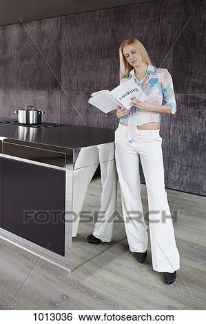 Woman reading cookery book in her modern kitchen. View Large Photo Image Stock Photograph - Woman reading cookery book in her modern kitchen.. Fotosearch