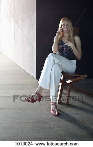 Woman sitting chatting on phone and smiling. View Large Photo Image Picture - Woman sitting chatting on phone and smiling.. Fotosearch