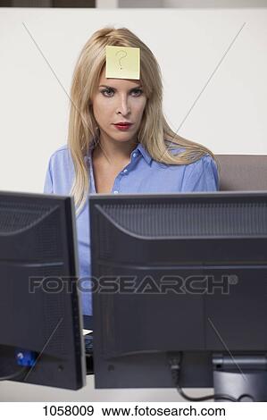 Woman staring at computer with adhesive note on her forehead View Large Photo Image Stock Photo - Woman staring at computer with adhesive note on her forehead . Fotosearch
