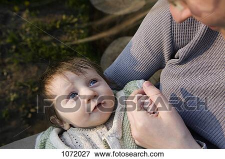 Stock Photo - A baby staring up into the face of her mother, focus on baby. Fotosearch