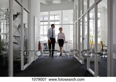 A businessman and businesswoman walking down a corridor together View Large Photo Image Stock Photo - A businessman and businesswoman walking down a corridor together. Fotosearch