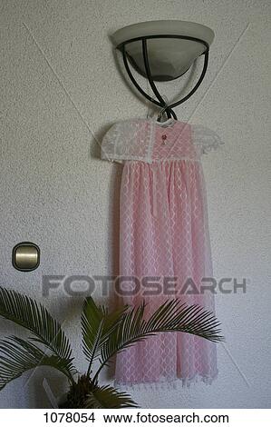 Picture - A christening gown hanging on a light fixture. Fotosearch