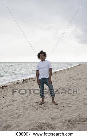 A cool young man standing on a beach, front view View Large Photo Image Stock Photo - A cool young man standing on a beach, front view. Fotosearch
