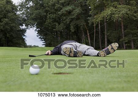 A distraught golfer lying on putting green with ball at the edge of hole View Large Photo Image Stock Image - A distraught golfer lying on putting green with ball at the edge of hole. Fotosearch
