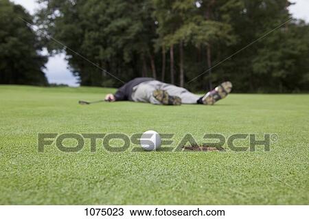 A distraught golfer lying on putting green with ball at the edge of hole View Large Photo Image Stock Image - A distraught golfer lying on putting green with ball at the edge of hole. Fotosearch