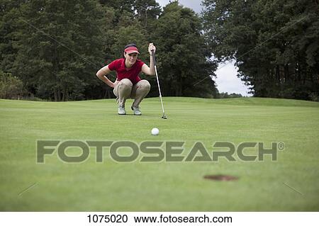 A female golfer crouching down studying the distance to the hole View Large Photo Image Stock Image - A female golfer crouching down studying the distance to the hole. Fotosearch