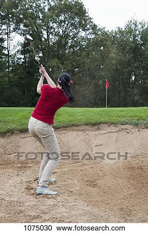 A female golfer hitting a ball out of a sand trap View Large Photo Image Stock Image - A female golfer hitting a ball out of a sand trap. Fotosearch