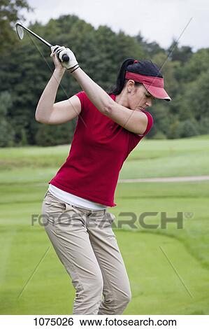 A female golfer preparing to swing her club View Large Photo Image Stock Photograph - A female golfer preparing to swing her club. Fotosearch