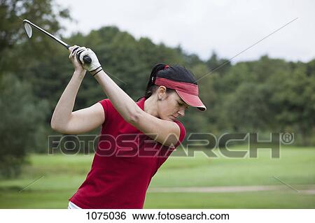 A female golfer preparing to swing her club View Large Photo Image Stock Photograph - A female golfer preparing to swing her club. Fotosearch