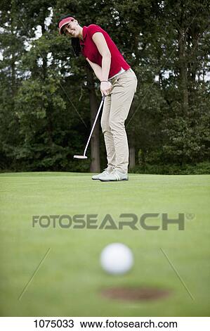 A female golfer putting, golf ball at edge of hole View Large Photo Image Stock Image - A female golfer putting, golf ball at edge of hole. Fotosearch