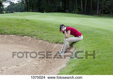 A female golfer sitting at the edge of sand trap, head in hands View Large Photo Image Picture - A female golfer sitting at the edge of sand trap, head in hands. Fotosearch