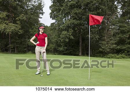 Picture - A female golfer standing on a putting green. Fotosearch