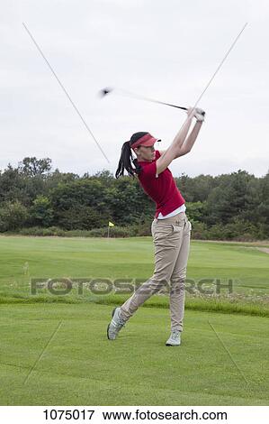A female golfer swinging her golf club, teeing off View Large Photo Image Stock Photo - A female golfer swinging her golf club, teeing off. Fotosearch