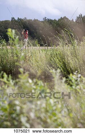 A female golfer teeing off, focus on background View Large Photo Image Stock Image - A female golfer teeing off, focus on background. Fotosearch