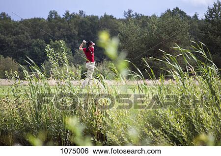 A female golfer teeing off, focus on background View Large Photo Image Stock Photograph - A female golfer teeing off, focus on background. Fotosearch