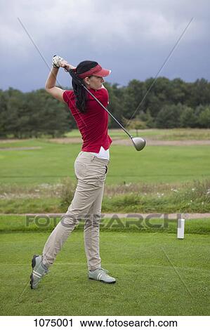 Stock Image - A female golfer teeing off. Fotosearch