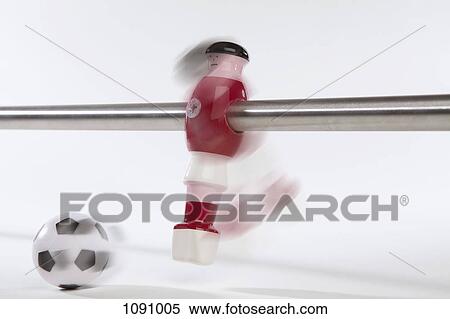 Stock Photography - A foosball figurine kicking a soccer ball, blurred motion. Fotosearch