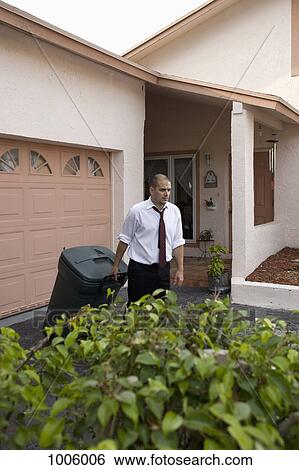 A frowning man pulling a trash can down his driveway View Large Photo Image Stock Photograph - A frowning man pulling a trash can down his driveway. Fotosearch