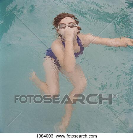 Stock Image - A girl holding nose underwater. Fotosearch