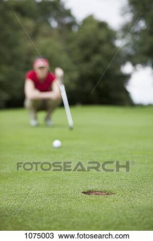 A golfer crouching down studying the distance to the hole, focus on hole View Large Photo Image Stock Image - A golfer crouching down studying the distance to the hole, focus on hole. Fotosearch