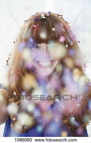 Stock Image - A grinning woman with falling confetti. Fotosearch